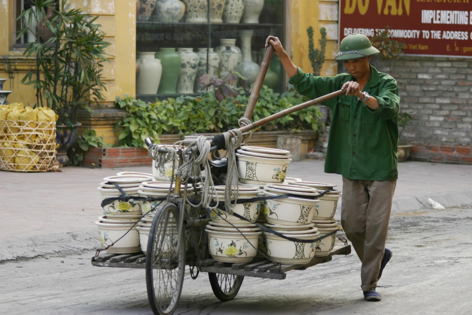 A vendor wheeling a bicycle loaded with ceramics in Bat Trang