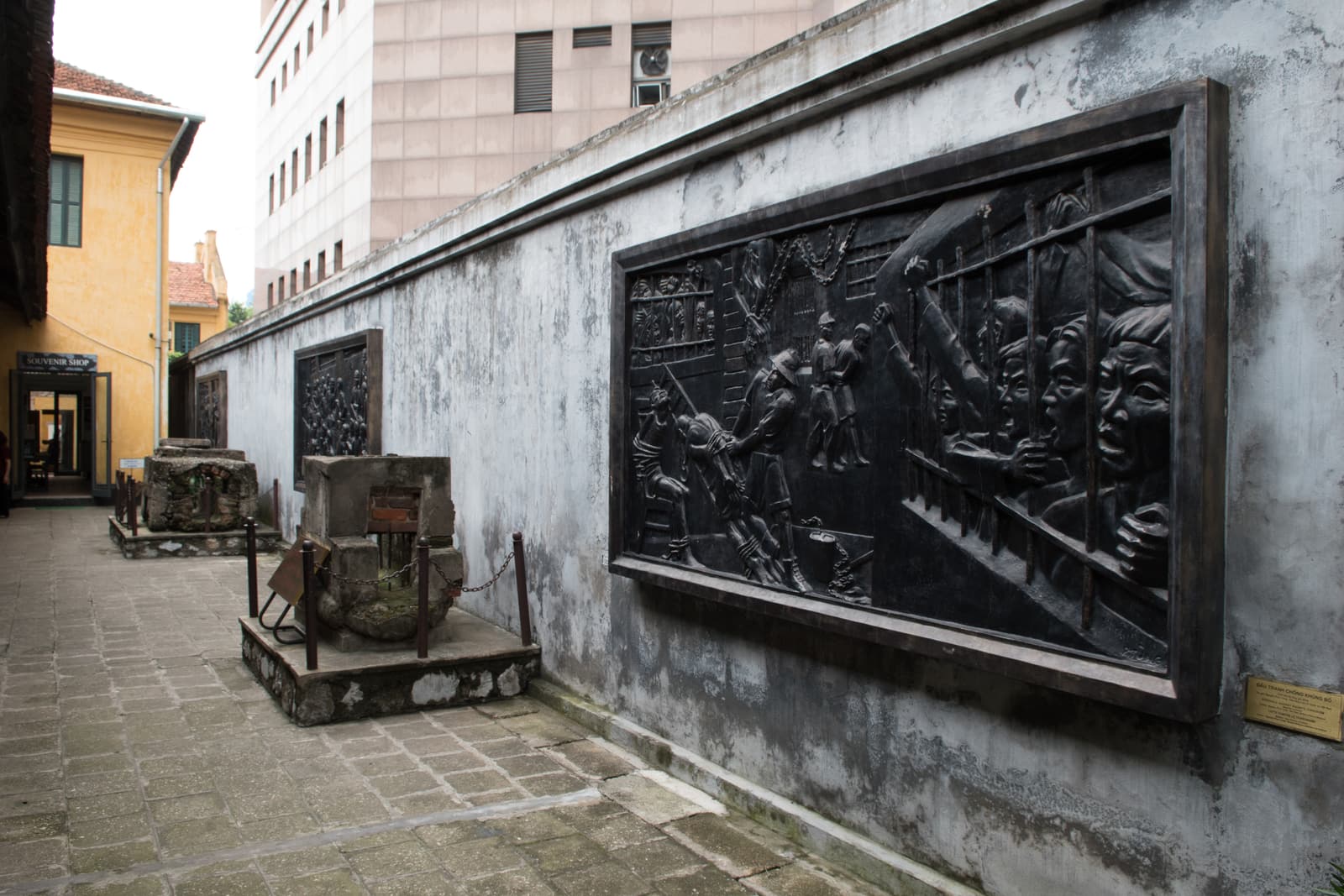 A courtyard of the Hoa Lo Prison museum with a bronze relief